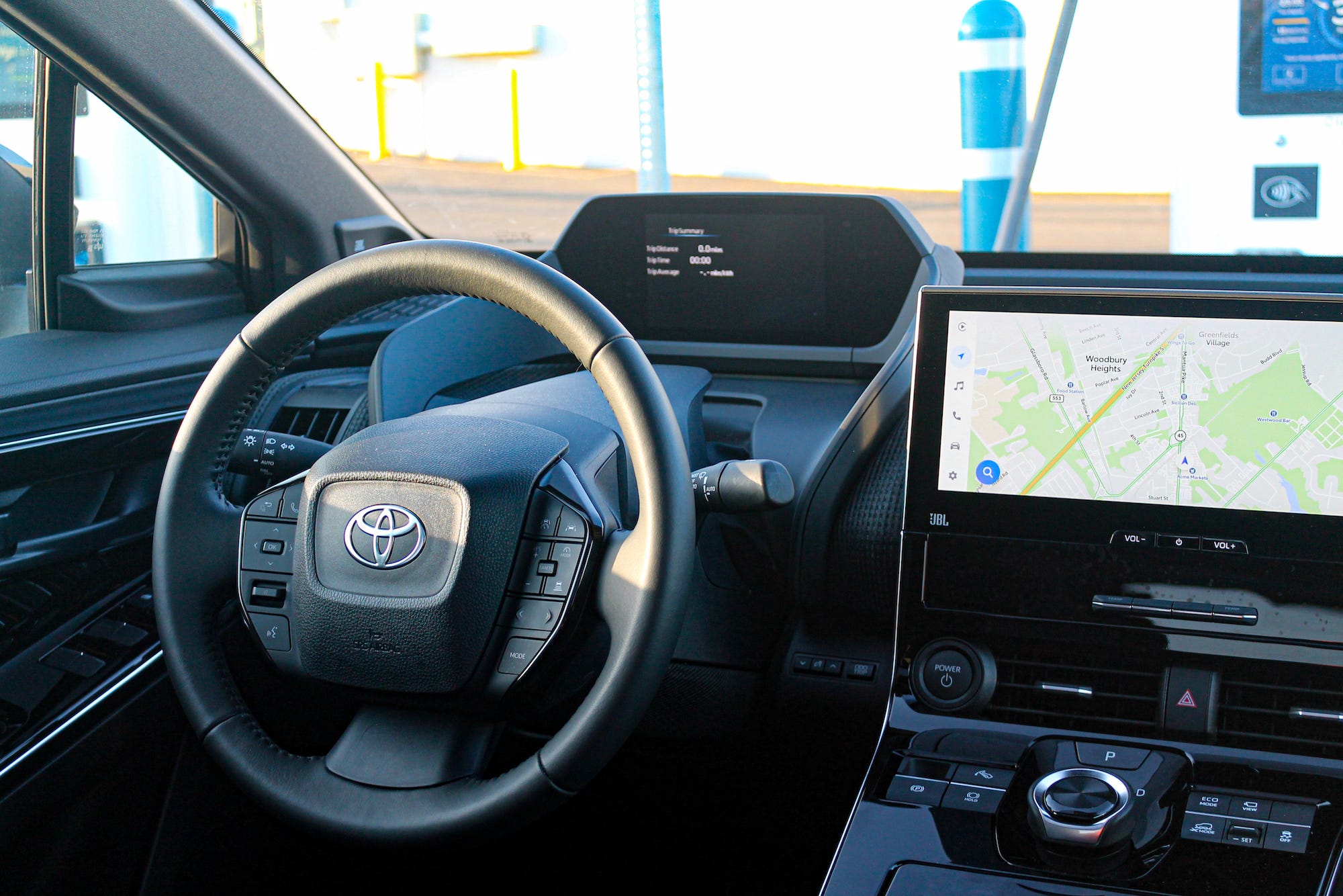 Roda kemudi dan layar pada SUV elektrik Toyota bZ4X AWD Limited 2023, dilihat dari jok belakang.